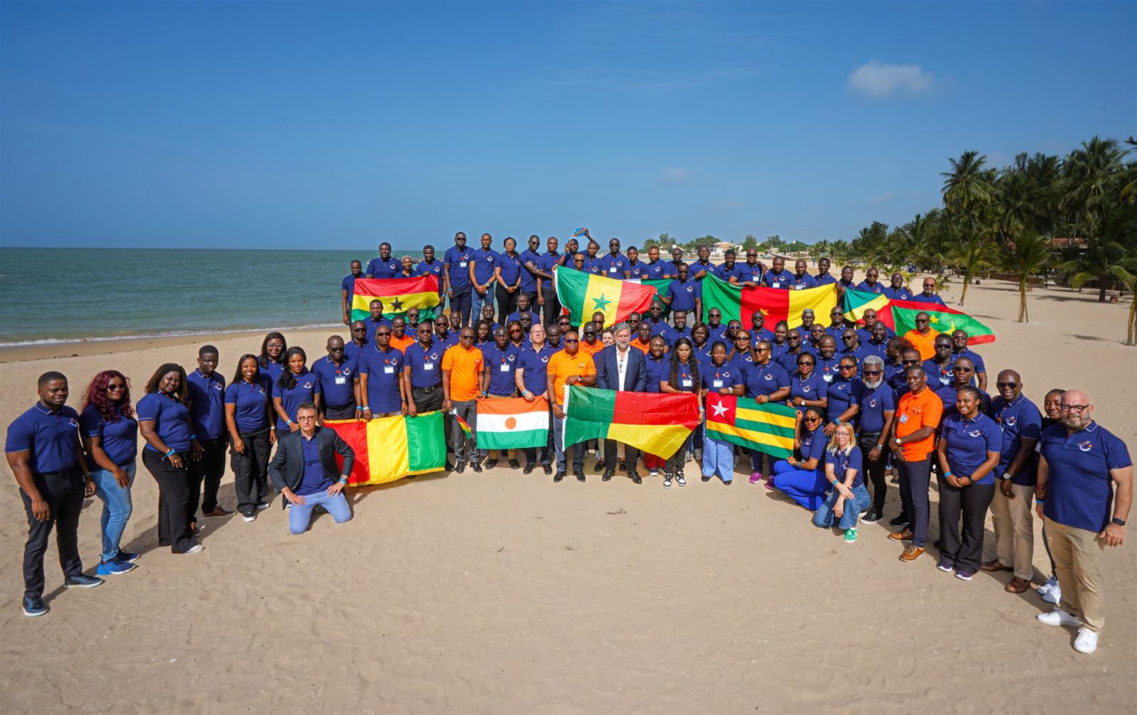 Équipe Servier Afrique de l'Ouest et du Centre réunie sur une plage avec les drapeaux de leurs pays